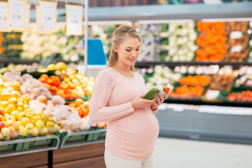 happy pregnant woman with juice at grocery store