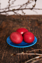 Three Easter eggs of red color on a blue plate