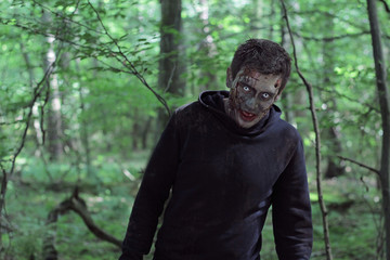 Zombie in a jacket with a hood in a forest.