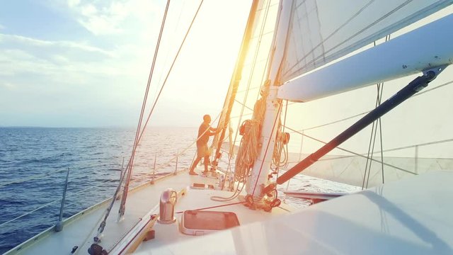 Mann auf Segelyacht / Segelboot segelt in die Abendsonne