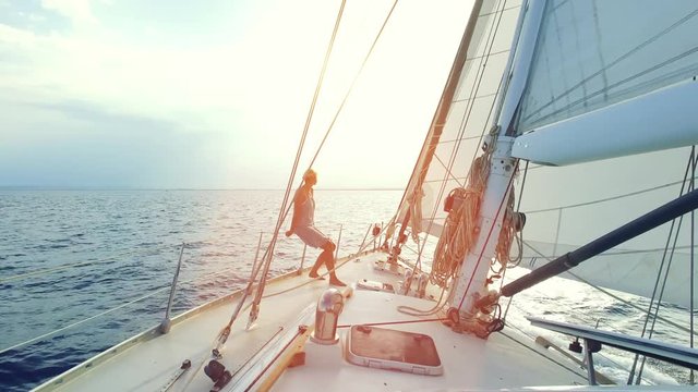 woman on big sail boat sailing the ocean - nice sun flares