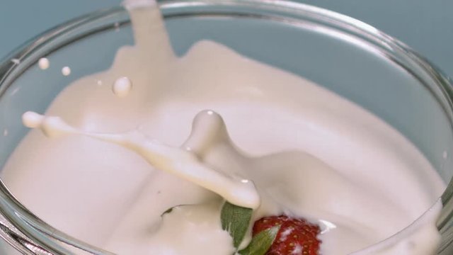 Fraise tombant dans un bol de cr&egrave;me fraiche slowmotion