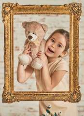 Indoor portrait of an expressive adorable young little girl and her Teddy bear friend seen from an...