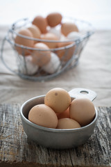 Farm fresh chicken eggs. A wire basket with more eggs in the background 