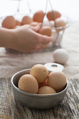 Farm fresh chicken eggs . Female hands and a basket with more eggs in the background. 