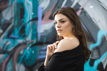 Obraz na płótnie Canvas Beautiful woman against street art graffiti wall with naked shoulder