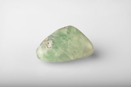 Polished stone agate green prehnite on a gray background.
