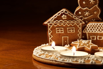 Homemade gingerbread house lit by candles on a dark background. Christmas dessert 