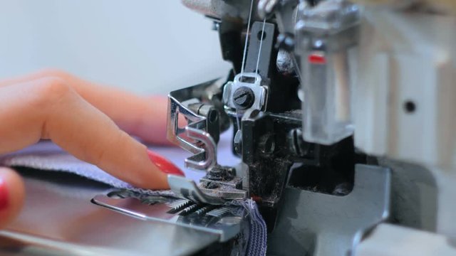Professional tailor, seamstress using overlocking sewing machine. Fashion and tailoring concept