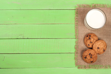 Fototapeta na wymiar glass of milk with oatmeal cookies on a green wooden background with copy space for your text. Top view