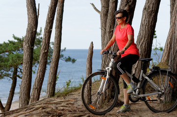 Kobieta na rowerze nad brzegiem morza.