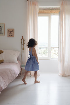 petite fille qui regarde par la fenêtre dans sa chambre