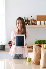 Young woman using a tablet computer to cook in her kitchen