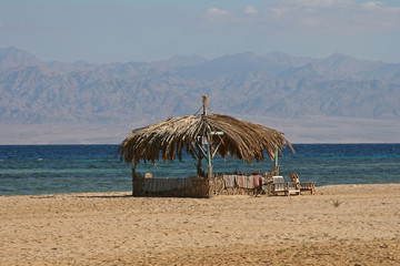 Bungalow and two wooden chairs on the shore of the Suez Canal in Egypt.