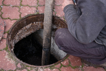 man pumping sewage from the drain hole