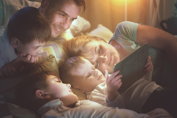 Happy family together watching movie on tablet computer in dark room