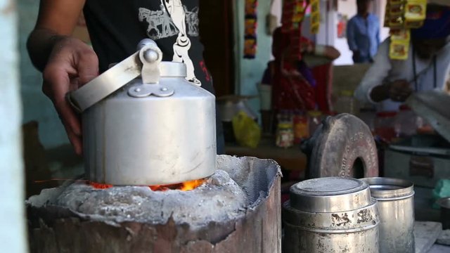 Man boiling chai in a pot and pouring it to a cup at stand in Jodhpur.