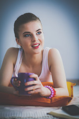 Smiling young woman lying on a white floor with pillow