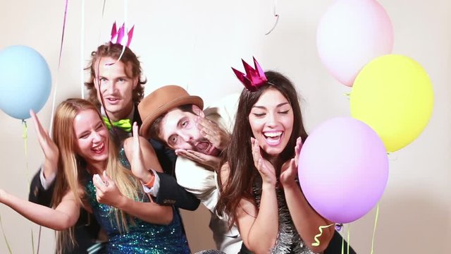 Four young crazy friends having great time in party photo booth