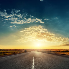 low sun in dramatic sky over asphalt road