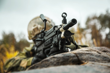Norwegian Rapid reaction special forces FSK soldier firing in the forest. Field camo uniforms,...