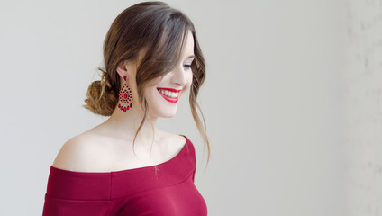 Portrait of young smiling beautiful woman in dress with earrings