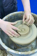 The master teaches the child, a student of pottery. Helps to make out of clay on a Potter's wheel a small jug.