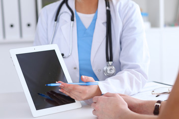 Close up of a doctor and  patient hands while phisician pointing into tablet computer monitor. Medicine and health care concept