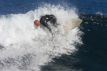 A surfer makes a turn in a breaking wave.