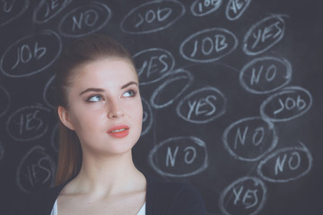 Young woman is standing on blackboard background and thinking: yes or no