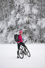 A women mountain biking across a snowy landscape looks back and smiles.