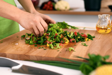 Close up of  woman's hands cooking in the kitchen. Housewife slicing ​​fresh salad. Vegetarian and healthily cooking concept