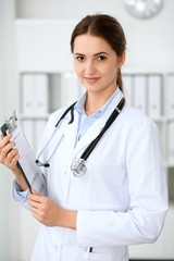 Latin american doctor woman standing with arms crossed and smiling at hospital. Physician ready to examine patient.  Health care, insurance and help concept. Physician ready to examine patient