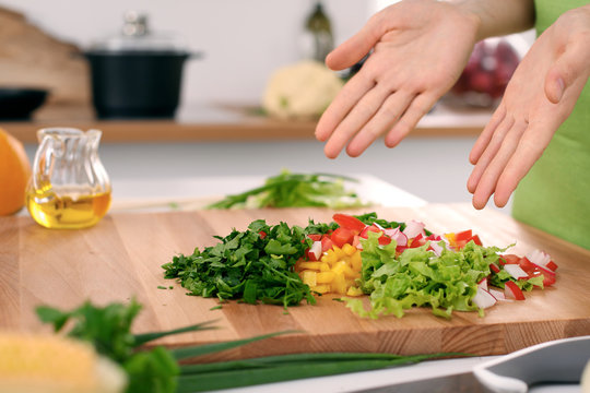 Close up of  woman's hands cooking in the kitchen. Housewife offering ​​fresh salad. Vegetarian and healthily cooking concept