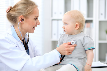 Pediatrician is taking care of baby in hospital. Little girl is being examine by doctor with stethoscope. Health care, medicine and help concept.