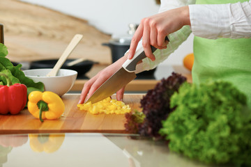 Closeup of human hands cooking vegetables salad in kitchen on the glassr table with reflection. Healthy meal and vegetarian concept