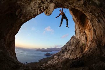 Foto op Canvas Rock climber gripping handhold on ceiling in cave © Andrey Bandurenko