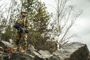 Fototapeta premium Norwegian Rapid reaction special forces FSK soldier patrolling in the forest. Field camo uniforms, combat helmet and eye-wear goggles are on