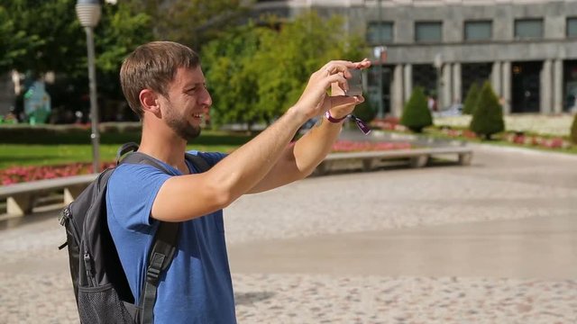 Male traveller taking panorama picture of cityscape on gadget, summer vacation