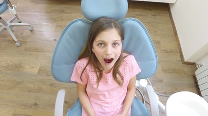 Close up of cute little girl at dentist, looking at camera and smiling