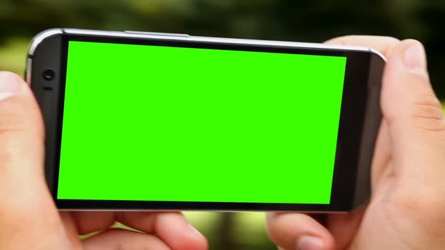 Person making 360 degree video on smartphone with green screen, alpha channel