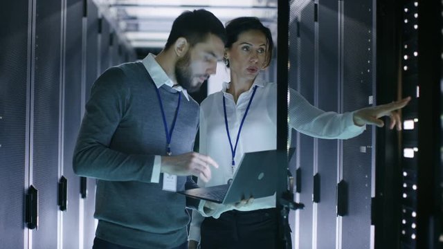 Male and Female Server Engineers Work on a Laptop in Data Center. He Opens Rack Server Cabinet. Shot on RED EPIC-W 8K Helium Cinema Camera.