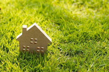 Small model of house over green grass dueling sunlight.