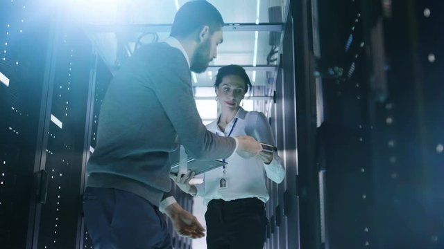 Male IT Engineer Takes out Hard Drives From Rack Server and Gives Them to Female IT Specialist. They're Working in Big Data Center.  Shot on RED EPIC-W 8K Helium Cinema Camera.
