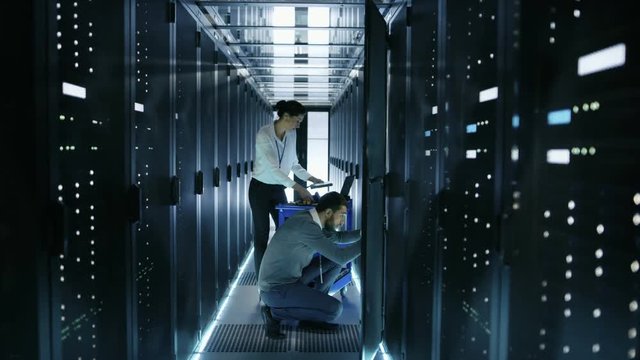 Male IT Engineer Takes out Hard Drives From Rack Server and Gives Them to Female IT Specialist, She Scans Them. They're Working in Big Data Center. Shot on RED EPIC-W 8K Helium Cinema Camera.