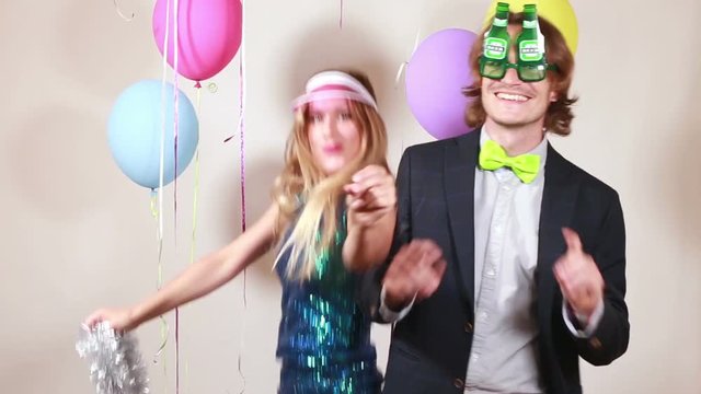 Cheerful beautiful woman and smiling man dancing in party photo booth 