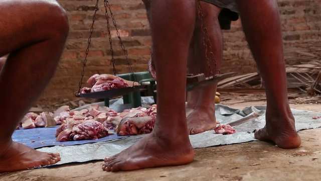 Men weighing meat of slaughtered animal.