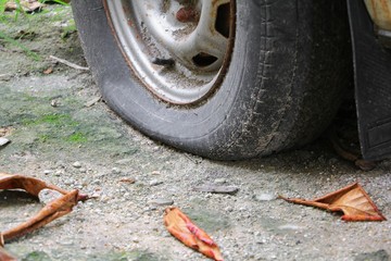 Close up wheel flat tire of the car old and cracked on the road