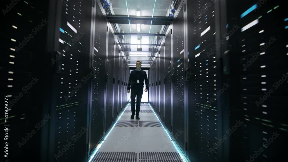 Wall mural Following Shot of IT Engineer Walking Through Data Center Corridor with Rows of Rack Servers. Shot on RED EPIC-W 8K Helium Cinema Camera.