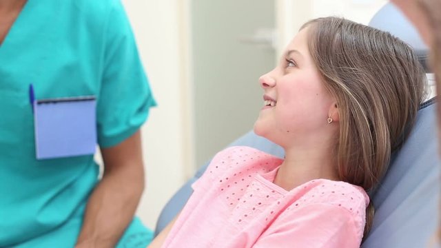 Cute little girl in dental chair shows with finger aching tooth